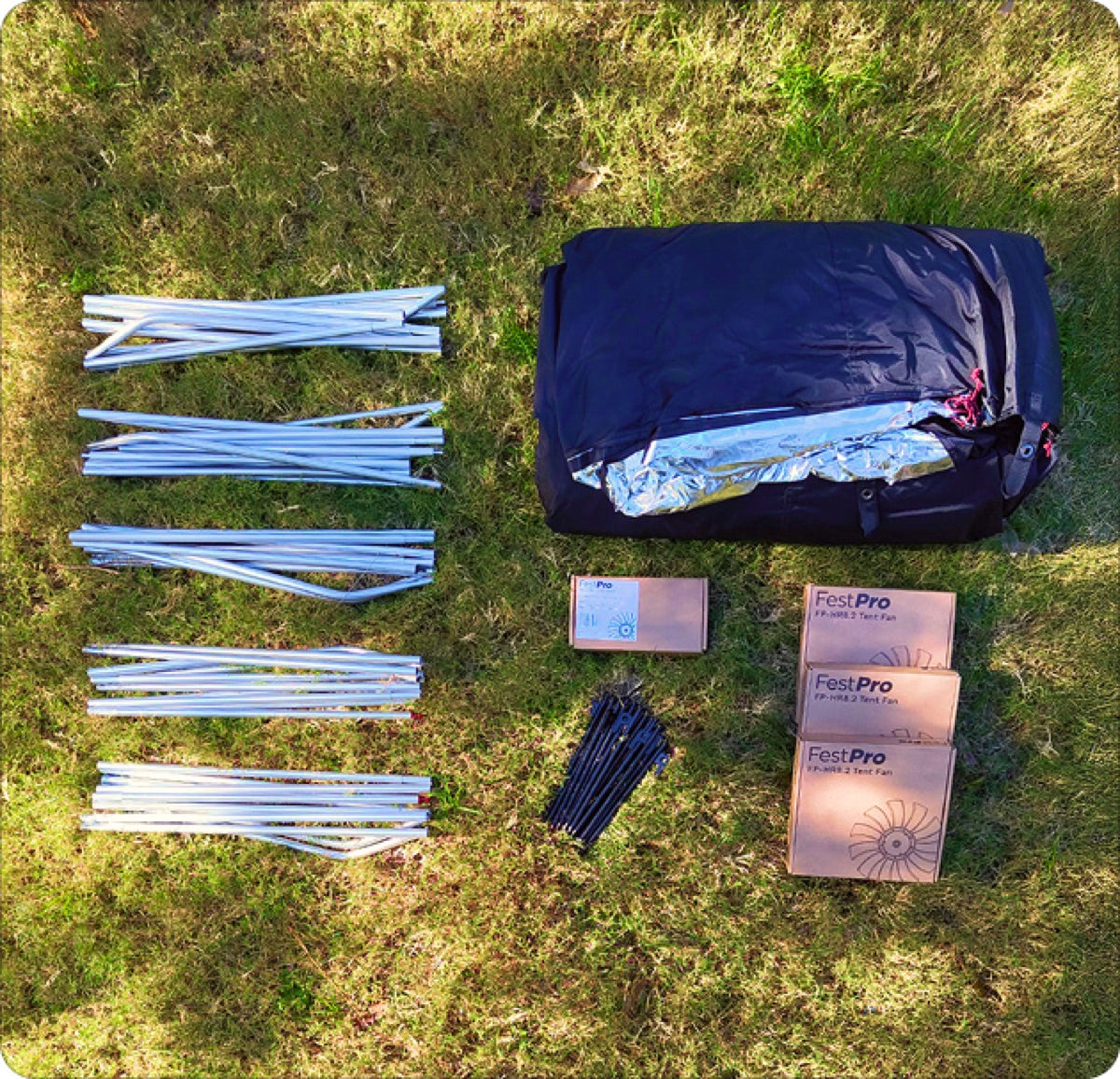 Siesta tent poles, fans and bag laid out on grass